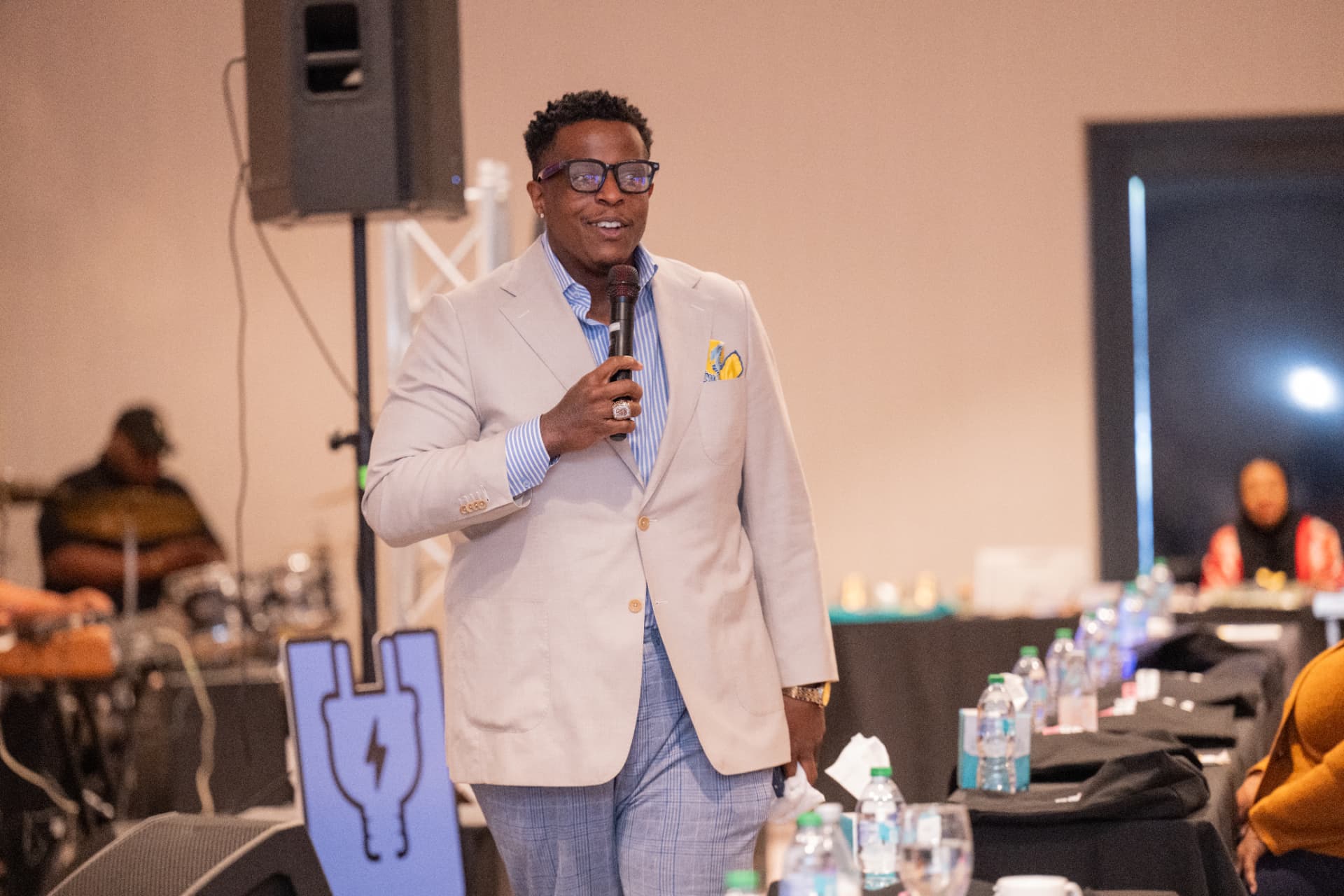 A speaker addressing the room with a microphone at UNPLUG 2026