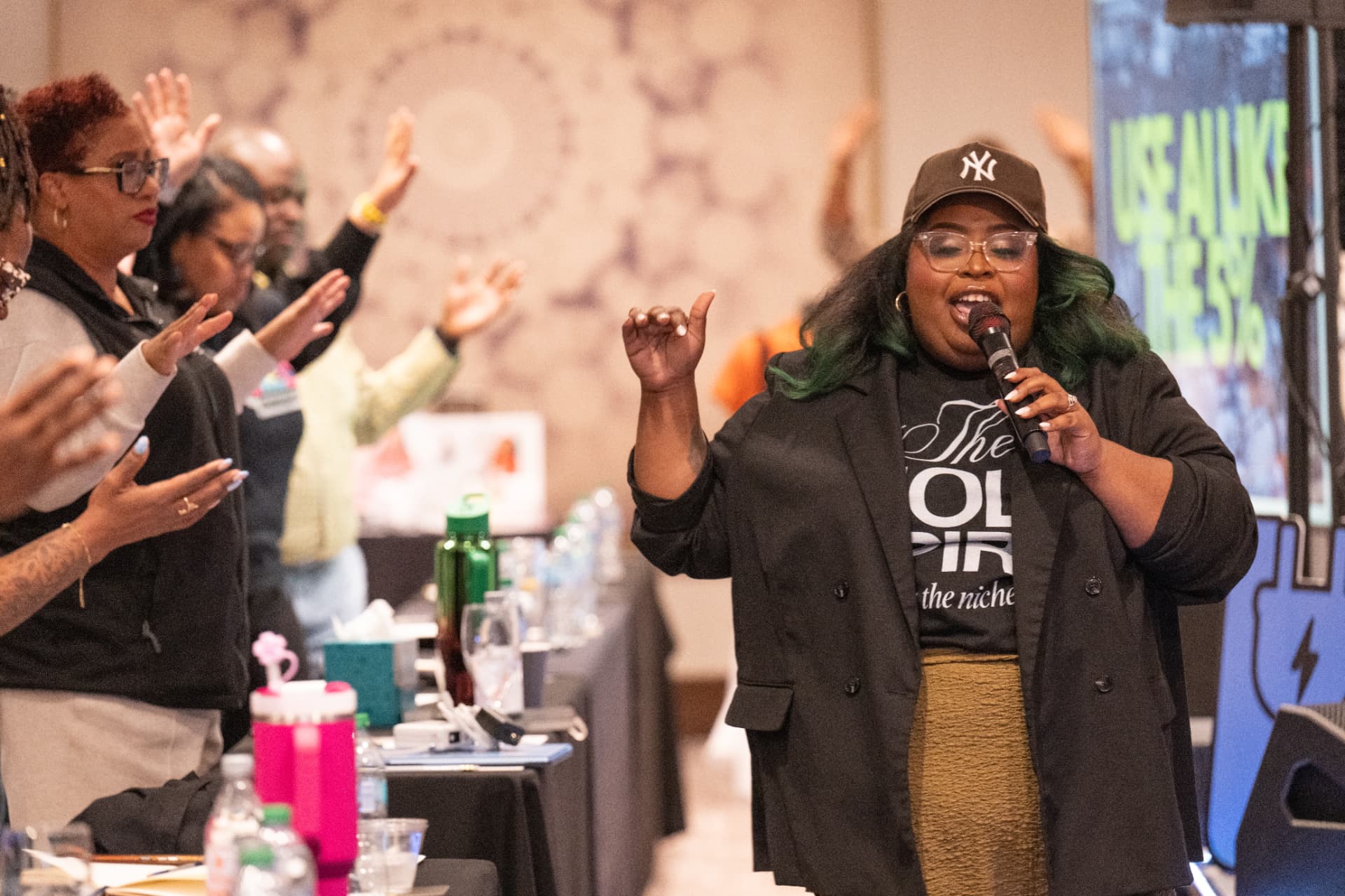 A speaker leading the room with a microphone at UNPLUG 2026